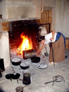Image of woman cooking by a fire to accompany blog post on Bent's Old Fort Kitchen