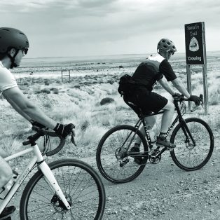 Two Cyclists passing the Santa Fe Trail sign