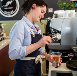 Employee making coffee at Kangaroo Coffee in the Trinidad Marketplace